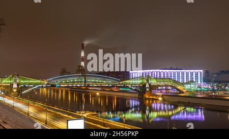 Vista del colorato ponte Bogdan Khmelnitsky illuminato di notte che si riflette nel fiume Moskova. Ponte pedonale sul fiume Moskva. Mosca Foto Stock