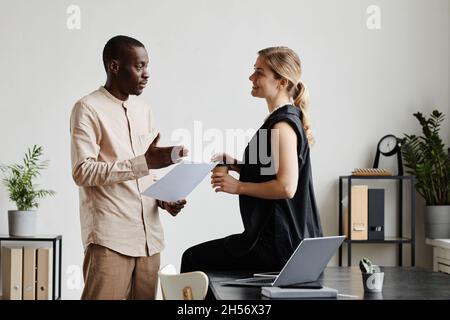 Ritratto minimo della vista laterale di due persone aziendali che discutono progetto per scrivania in ufficio, spazio di copia Foto Stock