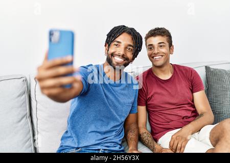 Due amici uomini fanno selfie dallo smartphone seduto sul divano a casa Foto Stock