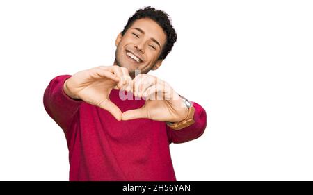Giovane bell'uomo che indossa abiti casual sorridente nell'amore facendo il simbolo del cuore forma con le mani. Concetto romantico. Foto Stock
