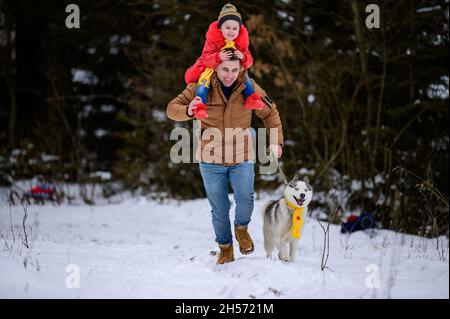 Famiglia felice su una passeggiata nel bosco con un Husky, jogging con un cane, divertimento inverno games.New Foto Stock
