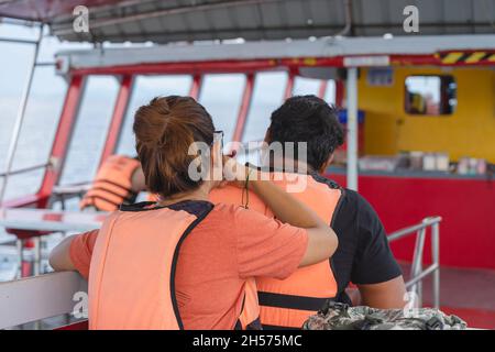 Vista posteriore dei passeggeri amanti in giubbotto di vita rilassante sul balcone che gode di vista dalla barca dell'isola di Samui in SEA.Happy coppia turisti casual fuori su Foto Stock