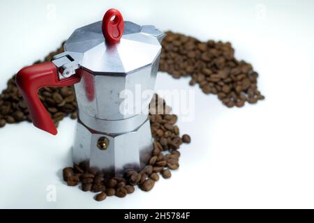 macchina per il caffè con filtro e chicchi di caffè su un tavolo bianco Foto Stock