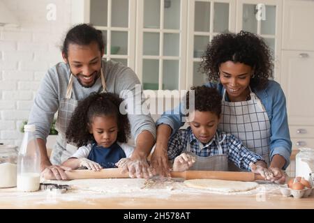 Allegro giovane coppia nera e bambini piccoli torta di cottura insieme Foto Stock