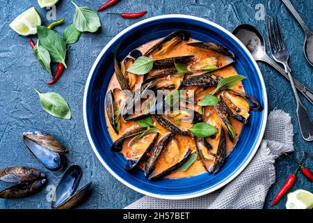 Deliziose cozze blu in una salsa piccante di curry rosso tailandese. Foto Stock