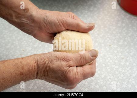Donna anziana impastando la pasta con le mani Foto Stock