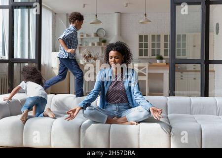 Calma mamma afroamericana meditando, mantenendo le emozioni sotto controllo Foto Stock