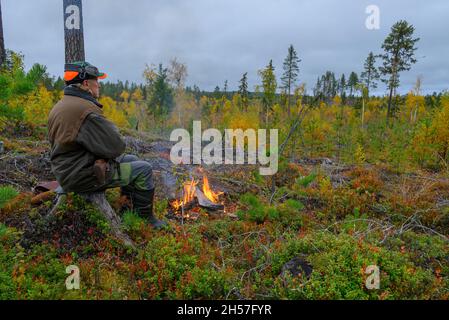 Hunter seduto su un moncone di fronte ad un fuoco in cerca di alci, foto dal Vasternorrland svezia. Foto Stock