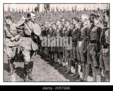 ADOLF HITLER saluta una parata in uniforme di Hitler Youth 'Hitlerjugend' indossando braccialetti swastika in un Rally di Norimberga degli anni '30 a Norimberga Germania nazista - Foto Stock