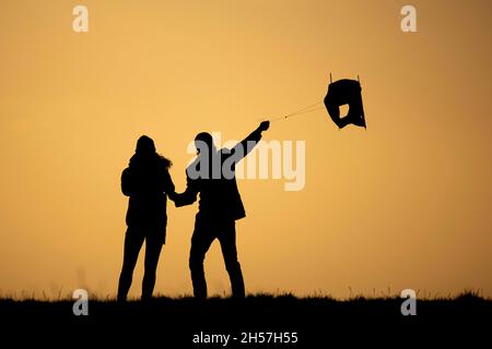 Berlino, Germania. 7 novembre 2021. La silhouette di due persone può essere visto volare un aquilone prima del tramonto a Berlino, 7 novembre 2021. Copyright: Florian Gaertner/photothek.de Credit: dpa/Alamy Live News Foto Stock