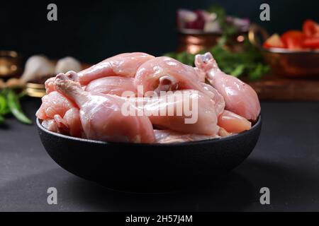 Pollo crudo biriyani tagliato senza pelle disposto su un contenitore nero con ingredienti da cucina posti nelle vicinanze. Foto Stock