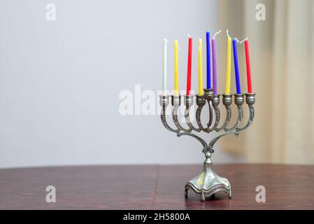 Festa ebraica Hanukkah sfondo con il menorah e candele colorate sul tavolo di legno in casa. Accogliente immagine menorah pronto per l'illuminazione. Foto Stock