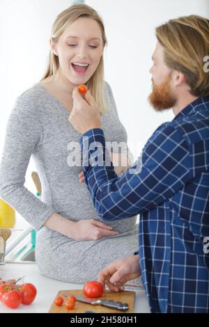 uomo che allatta una tomatoe alla moglie incinta Foto Stock