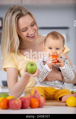 madre con il bambino che mangia una frutta Foto Stock