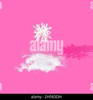 Un grande fiocco di neve 3D che cade in un mucchio di neve su sfondo rosa brillante. Design creativo delle vacanze invernali surreali. Banner o adver di Natale o Capodanno Foto Stock