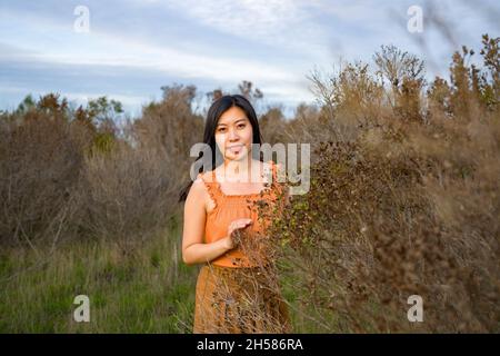 Giovane donna asiatica in colori autunnali a piedi nelle Marshlands Foto Stock