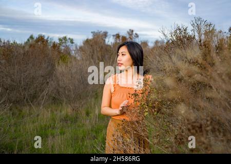 Giovane donna asiatica in colori autunnali a piedi nelle Marshlands Foto Stock