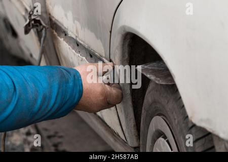 Riparazione della portiera posteriore della vettura. Eliminazione del corpo di trasporto rotto. Foto Stock