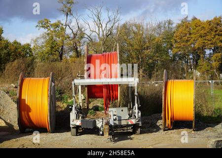 Grandi bobine di nuovo cavo in fibra ottica in rosso e arancione, espansione di Internet ad alta velocità nelle regioni rurali. Garbsen Berenbostel, Germania. Foto Stock