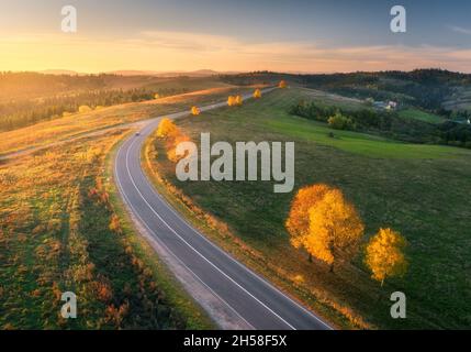 Vista aerea della strada tortuosa in autunno foresta al tramonto Foto Stock