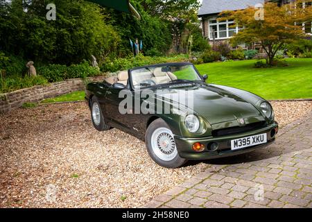 MG RV8 parcheggiato su una guida in ghiaia ag dietro una casa in pietra e surburbano Foto Stock