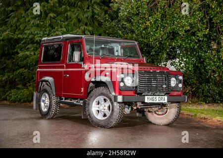 Modello recente, Land Rover Defender 90, parcheggiato in un parcheggio in un ambiente rurale durante una giornata bagnata Foto Stock