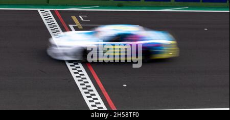 Gara auto sfocata movimento attraversamento finale linea a scacchi su asfalto pista, concetto di vittoria e obiettivo raggiunto Foto Stock