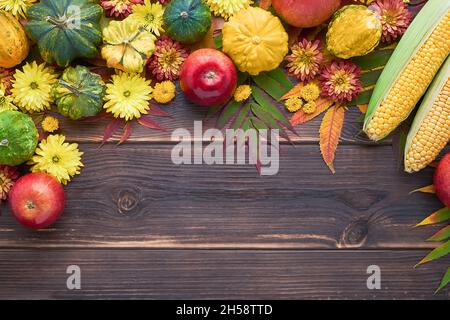 Sfondo autunnale con zucche, mele e foglie colorate su un tavolo di legno scuro. Felice giorno del Ringraziamento concetto. Disposizione piatta, spazio di copia per il testo Foto Stock