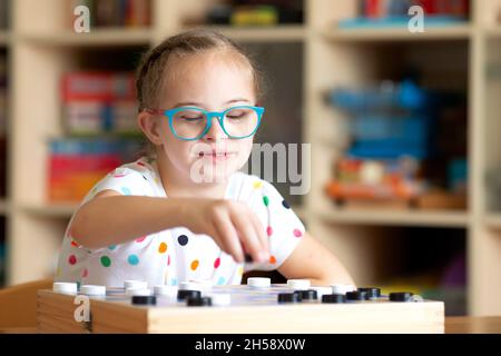 Ragazza con sindrome di Down gioca Dama con la sorella in quarantena Foto Stock