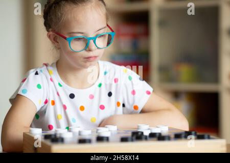 Ragazza con sindrome di Down gioca Dama con la sorella in quarantena Foto Stock