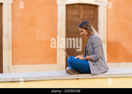 Donna seria che scrive sul portatile in città Foto Stock