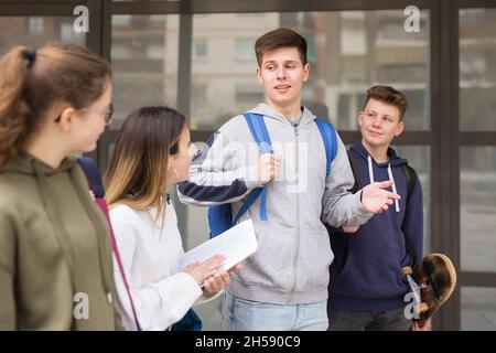 Gli studenti che camminano fuori dalla scuola sono spensierati Foto Stock