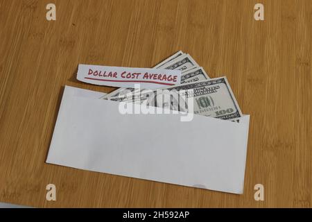 Foto concettuale, carta di denaro all'interno della busta bianca e del testo costo medio del dollaro, o investimento della regola dorata di DCA Foto Stock