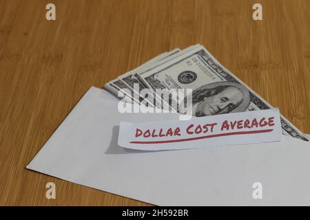 Foto concettuale, carta di denaro all'interno della busta bianca e del testo costo medio del dollaro, o investimento della regola dorata di DCA Foto Stock