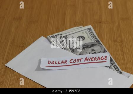 Foto concettuale, carta di denaro all'interno della busta bianca e del testo costo medio del dollaro, o investimento della regola dorata di DCA Foto Stock