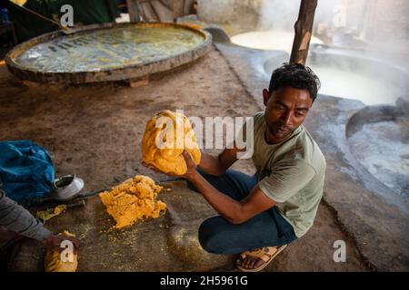 Roorkee, India. 6 novembre 2021. Un lavoratore mostra una palla jaggery rotonda durante il lavoro, ad un'unità di produzione jaggery nella parte inferiore di Roorkee.jaggery che fa da succo di canna da zucchero è un'industria rurale tradizionale in molte parti dell'India. Più del 70% della produzione mondiale di jaggery è fatta dall'India. Credit: SOPA Images Limited/Alamy Live News Foto Stock