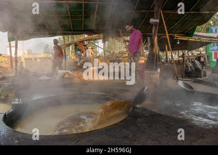 Roorkee, India. 6 novembre 2021. Un operaio versa il succo di canna da zucchero denso in un altro contenitore mentre facendo il jaggery (confezione di zucchero di canna tradizionale).jaggery che fa dal succo di canna da zucchero è un'industria rurale tradizionale in molte parti dell'India. Più del 70% della produzione mondiale di jaggery è fatta dall'India. (Foto di Pradeep Gaur/SOPA Images/Sipa USA) Credit: Sipa USA/Alamy Live News Foto Stock