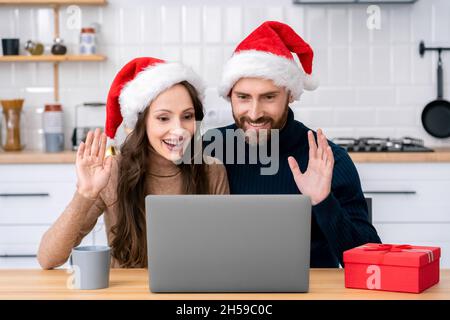 Felice coppia di famiglia a santa Hat fare videochiamata di Natale sul portatile Foto Stock