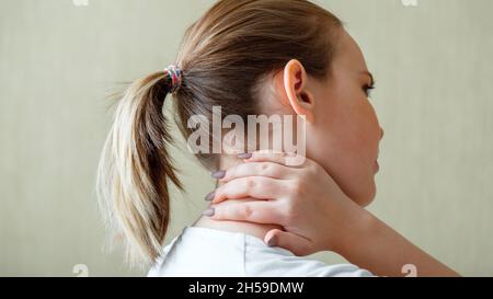 Dolore alla spalla del collo, vertebre cervicali. La donna tiene il collo con dolore spasmo del muscolo cervicale a mano a casa. Concetto medico sanitario. Banner web lungo Foto Stock