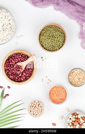 Fonte di proteine vegane. Fagioli, piselli, ceci, lenticchie, fagiolini, arachidi in ciotola su sfondo bianco. Cibo vegetariano sano. Foto Stock