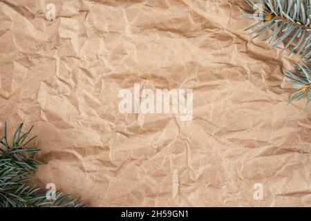 Immagine di sfondo di carta ruvida kraft riciclato e sbriciolato con rami di albero di Natale. Vista dall'alto. Spazio di copia Foto Stock