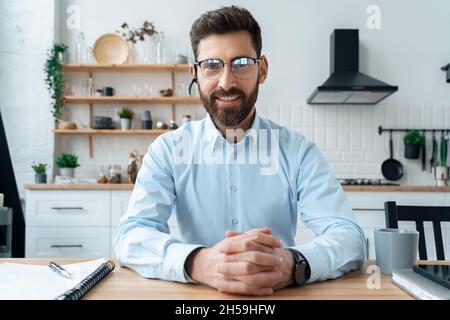 Uomo d'affari sorridente e intelligente seduto alla scrivania parlare con la webcam per videochiamare Foto Stock