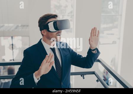 Uomo d'affari in tuta utilizzando occhiali per realtà virtuale in ufficio Foto Stock