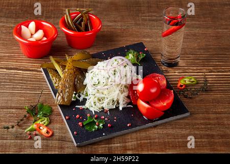 Verdure marinate sottaceto: Cetrioli, pomodori, cavolo e carote, verdure colorate con aceto su tavola di legno Foto Stock