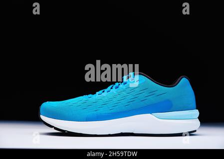 Sneaker Blue running da vicino. Scarpa sportiva maschile su sfondo nero. Concetto di fitness Foto Stock