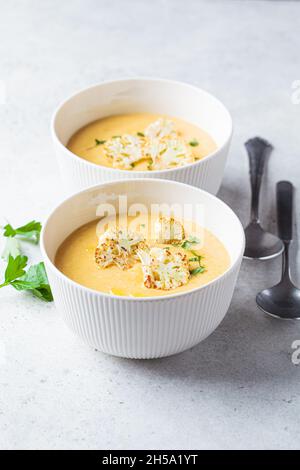 Zuppa vegetariana di formaggio cremoso con cavolfiore in un recipiente bianco. Concetto di cibo vegano sano. Foto Stock