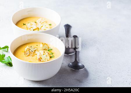 Zuppa vegetariana di formaggio cremoso con cavolfiore in un recipiente bianco. Concetto di cibo vegano sano. Foto Stock