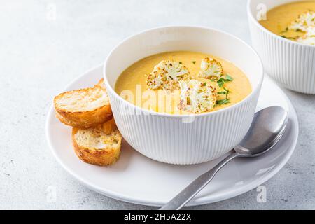 Zuppa vegetariana di formaggio cremoso con cavolfiore in un recipiente bianco. Concetto di cibo vegano sano. Foto Stock