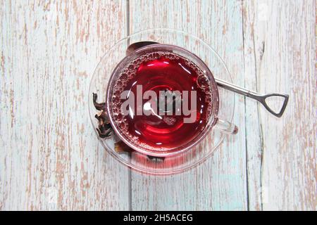 Tè Hibiscus : in una tazza trasparente su un tavolo di legno. Vista dall'alto. Foto Stock