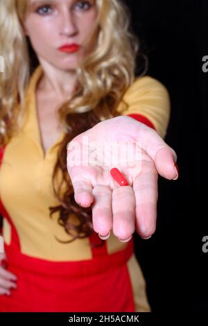 Cameriera con Red Nail Polish Holding Red pill Foto Stock